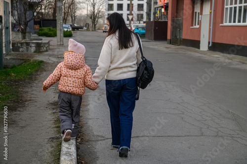 Mother Walking with Child in Urban Neighborhood Holding Drawings