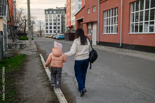 Mother Walking with Child in Urban Neighborhood Holding Drawings