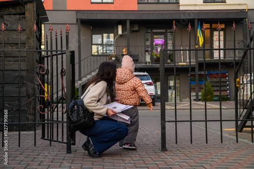 Mother Walking with Child in Urban Neighborhood Holding Drawings