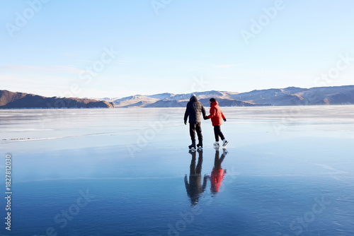 Fotografía A couple is skating on the frozen Lake Baikal. Transparent ice.