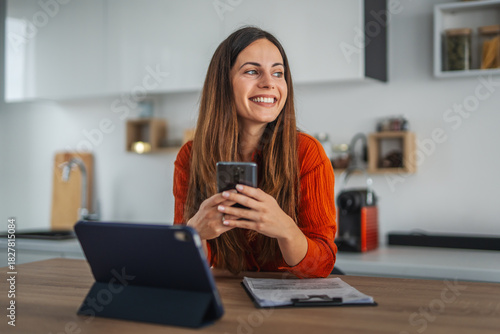 Happy woman using smart phone working from home office