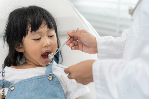 Dentist or dentist treating or examining a little girl teeth, Child receiving treatment from dentist, medicine, dentistry and healthcare, annual checkup, fluoride coating, tooth decayฃ