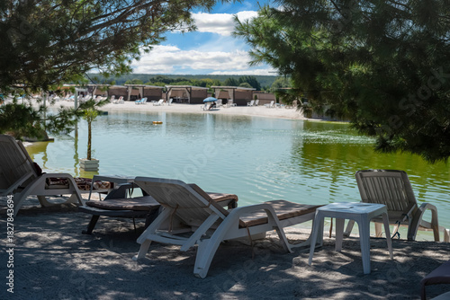 Wallpaper Mural White deck chairs by the lake in the shade between coniferous trees Torontodigital.ca