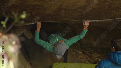 rock climbing outdoors on boulders in autumn woods. top view slow motion woman climber climbs crag bouldering reaching holds. strength and power. healthy sport lifestyle, active leisure.