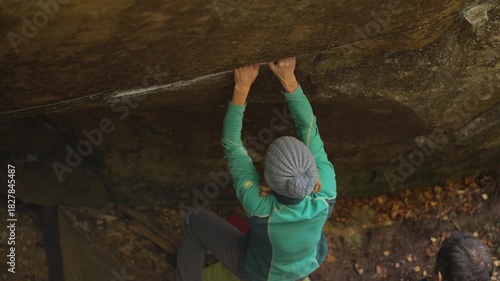 slow motion woman climber climbs crag bouldering reaching holds. strength and power. healthy sport lifestyle, active leisure. rock climbing outdoors on boulders in autumn forest.