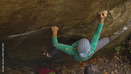 slow motion woman climber climbs crag bouldering reaching holds and making hard movements showing strength and power. healthy sport lifestyle, active leisure. rock climbing outdoors in autumn forest.