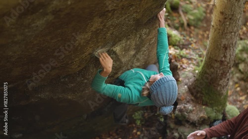 slow motion woman climber climbs crag bouldering reaching holds and making hard movements showing strength and power. healthy sport lifestyle, active leisure. rock climbing outdoors in autumn forest.