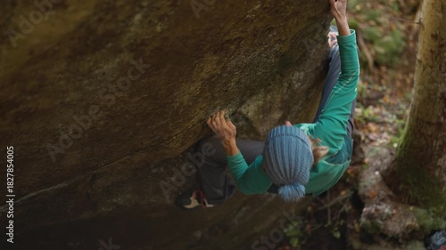 slow motion woman climber climbs crag bouldering reaching holds and making hard movements showing strength and power. healthy sport lifestyle, active leisure. rock climbing outdoors in autumn forest.