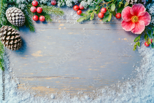 Rustic winter holiday border with pinecones and flowers on wood