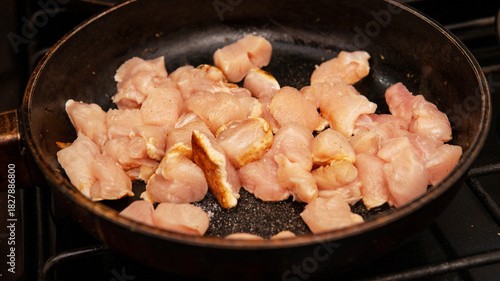 raw chopped chicken being sauteed in a frying pan