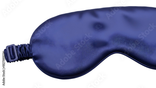 A close-up of a blue silk eye mask, lying on a dark background