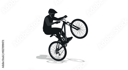 Dynamic silhouette of cyclist performing a wheelie on mountain bike