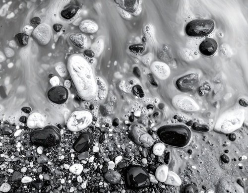 Black and white shot of wet rocks and flowing water on a beach, showing texture and motion in grayscale