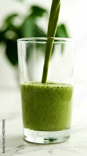 A glass of green liquid is poured into a glass. The liquid is green and he is a smoothie