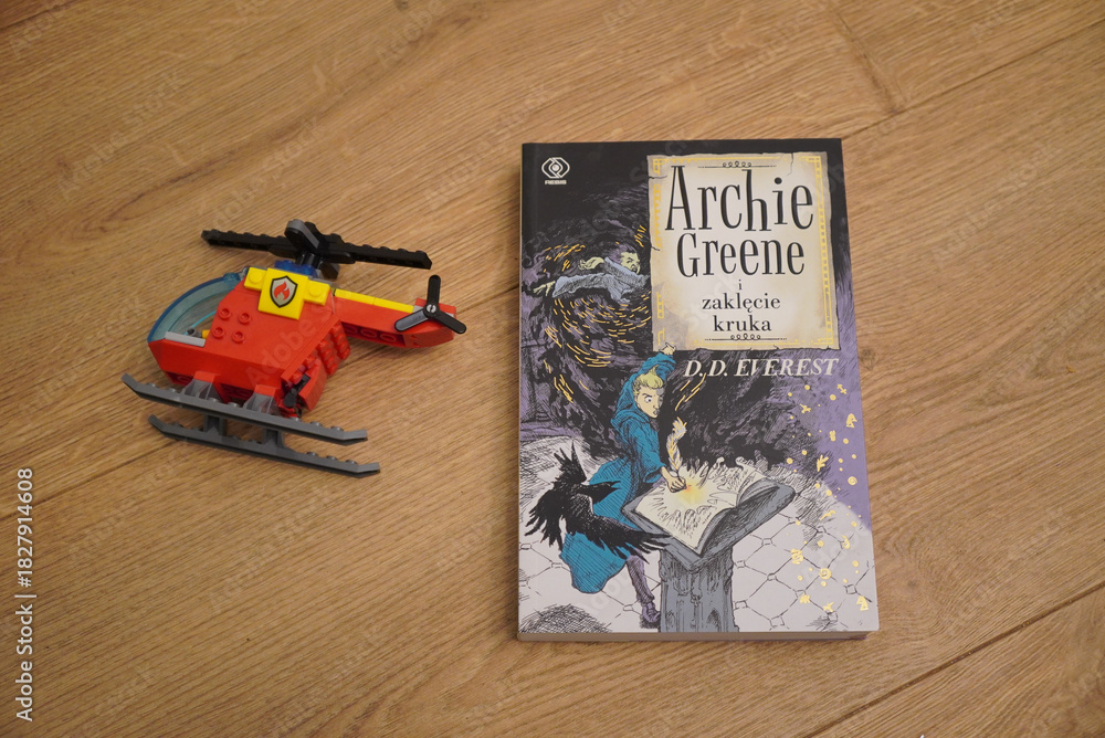 Naklejka premium A Lego helicopter and a book on a wooden surface, a creative composition