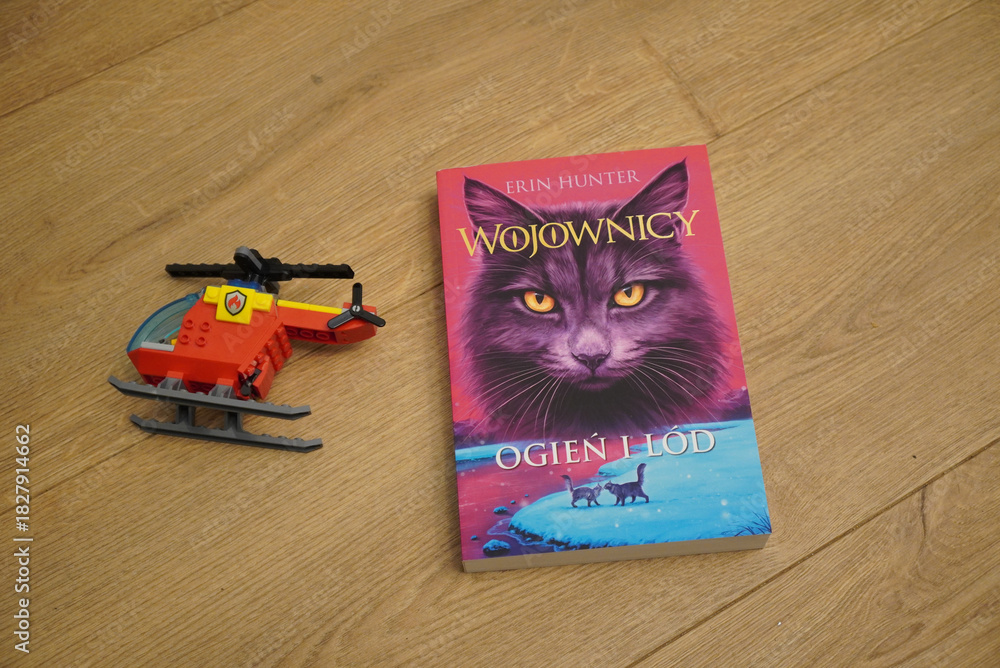 Fototapeta premium A Polish edition of the book 'Warriors: Into the Wild' with a toy helicopter