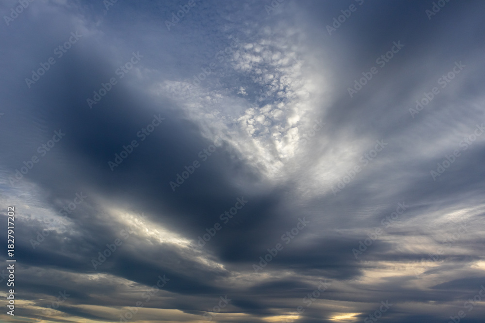 Fototapeta premium Layered grey clouds sweeping across a soft evening sky