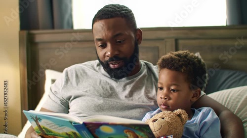 Warm, intimate video: African American father (mid-30s) reads vivid storybook to his son (5) on a plush bed with golden light and bokeh. Concept of family bonding and warmth