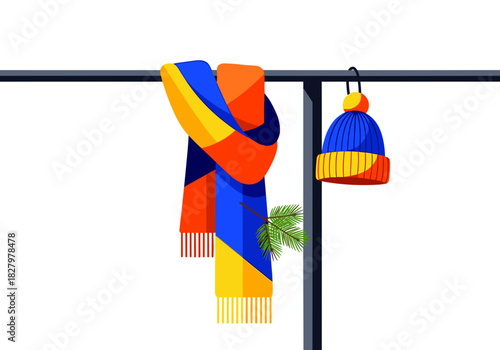 Colorful scarf and beanie hanging on a rail with pine sprig  