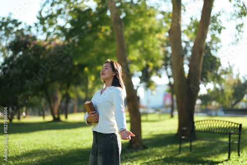 Woman enjoying sunshine in park with book