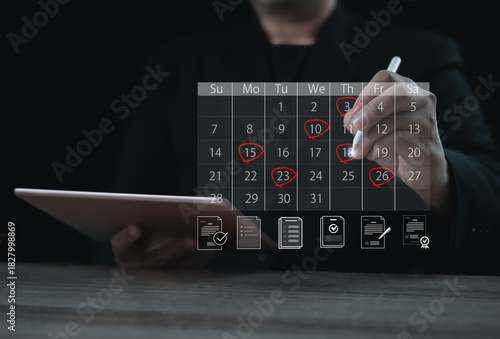 A planner marking important dates on a digital calendar using a stylus while holding a tablet. The highlighted days represent scheduling, organization, time management, reminders, and deadline prepara