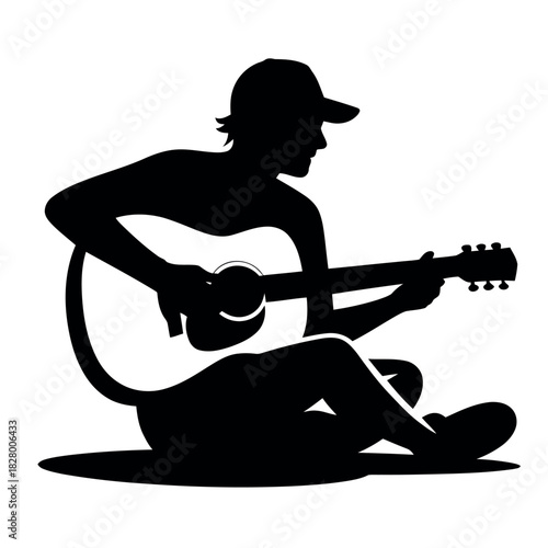 Silhouette of a person sitting and playing an acoustic guitar outdoors