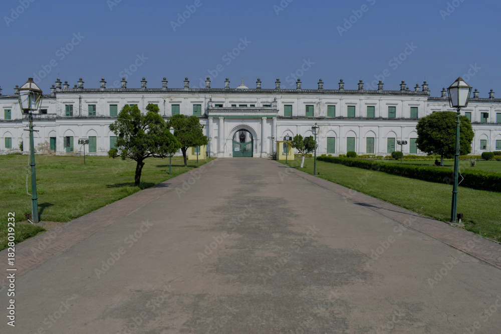 Obraz premium long white religious court building of 'nizamat imambara' with arched gateway, garden path, and heritage lamps at murshidabad, india