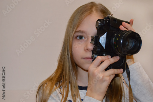 A girl holds an old camera in her hands