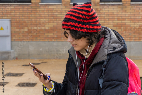 Teenager wearing cat ear hat using phone outdoors
