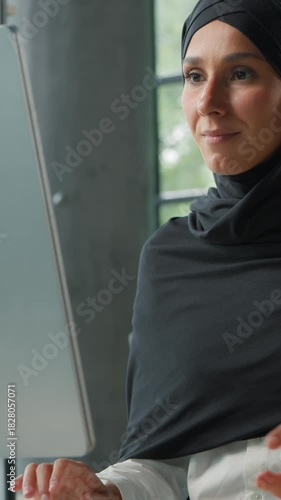 Arabian Muslim concentrated business woman in hijab working on computer in office Islamic businesswoman typing internet corporate software chatting with client smiling enjoying work female girl happy