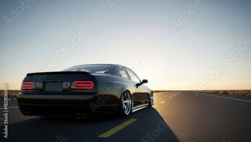 Sleek black sports car driving on highway at sunset