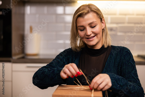 Woman joyfully unwrapping a gift in a modern kitchen at home during the morning
