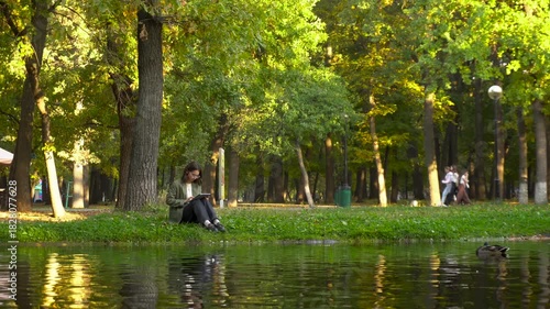 Young woman using tablet in riverside park, 4K