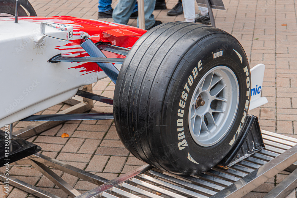 Naklejka premium White and red Formula 1 Toyota TF-108 car on pit stop stand, showcasing aerodynamic bodywork, rear wing, slick racing tires, front wing, nosecone, and wheel assembly - Kyiv, Ukraine 10-10-2024