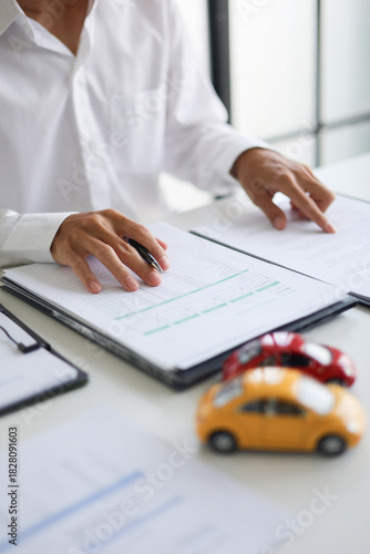 A man signing a contract for a car loan, lease, vehicle registration or insurance policy. Concept for Sales Contract, Financing Agreement, Insurance Policy, Vehicle Registration.
