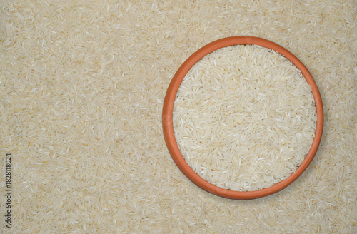 White Rice Grains in a Terracotta Bowl with Scattered Rice