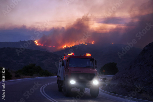 Foto Firefighting truck with flashing lights drives on a road towards a large wildfir