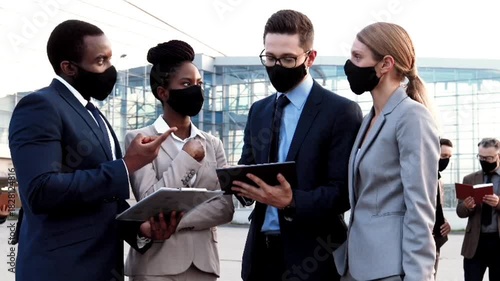 group of business man and woman talking together  with masks walking in the city street 