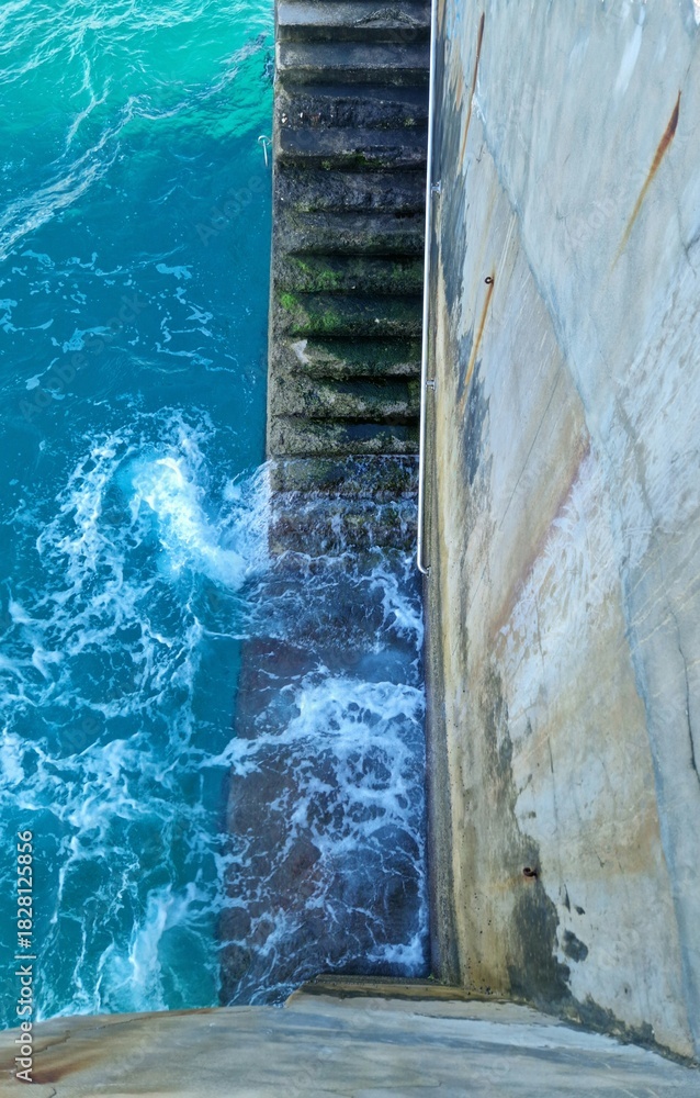 Fototapeta premium Stairs from the pier into the blue ocean swimming pool in the sea 