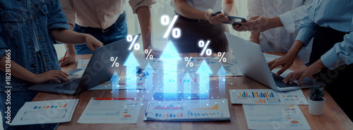 Foto A diverse team engages in business strategy discussions, examining growth percentages and data visuals amidst laptops and documents in a modern office space