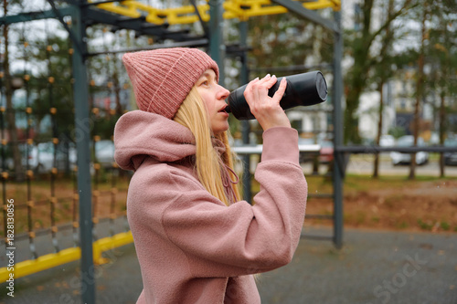 Young woman drinking water after outdoor workout