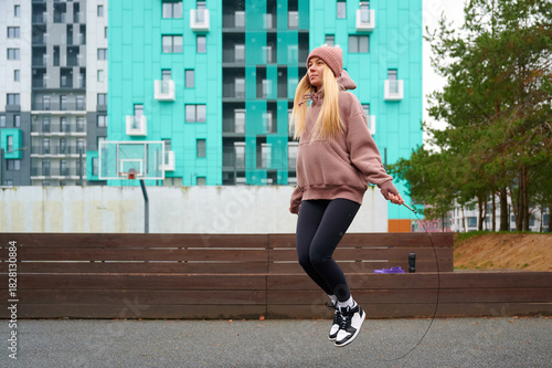 Obraz na plátně Young woman exercising with jump rope outdoors in urban area