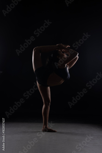 Dramatic silhouette of a woman performing an yoga . Artistic black and white studio fitness photography with rim lighting.