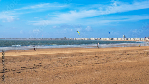 Sandy beach and sea with windsurfing and kitesurfing in the towns of Pornichet and La Baule in Brittany, France, in front of buildings typical of the region
