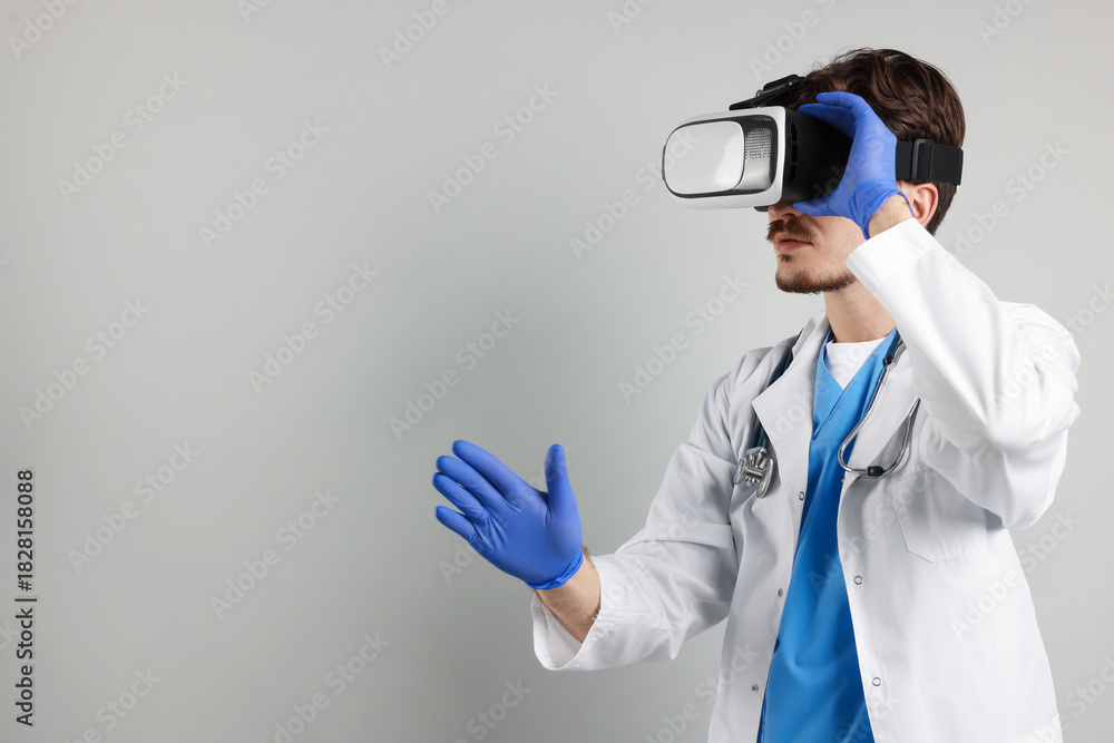 Naklejka premium Modern technology. Doctor using virtual reality headset on grey background. Space for text