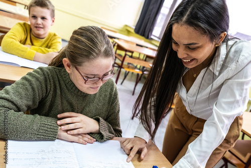 The teacher is looking over one student’s homework, giving calm guidance while checking their work. The classroom feels focused as the student waits for feedback.