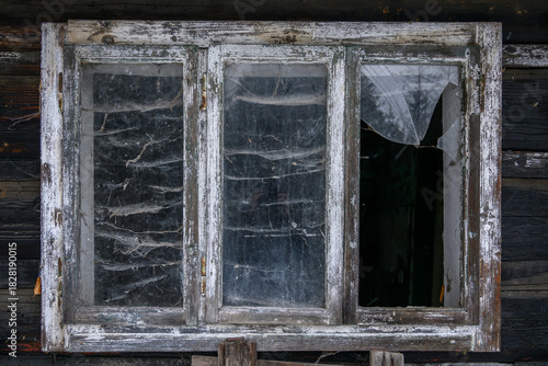 Outdoor view of a broken window of an old dilapidated wooden cottage.
