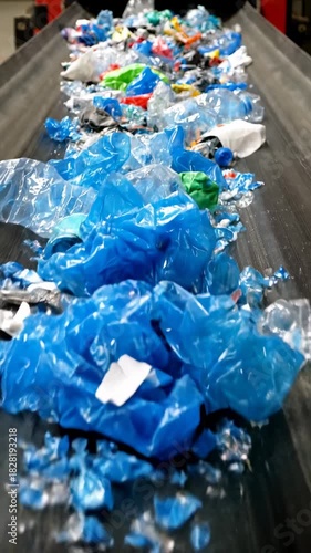 Discarded plastic waste moves along conveyor belt at recycling facility