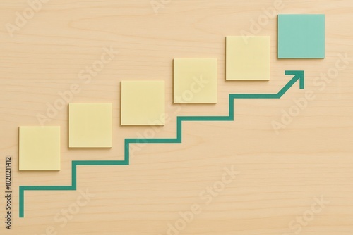 Conceptual progression depicted with color blocked post it notes arranged in a stair step pattern on a wooden background signifying growth creativity and strategic planning