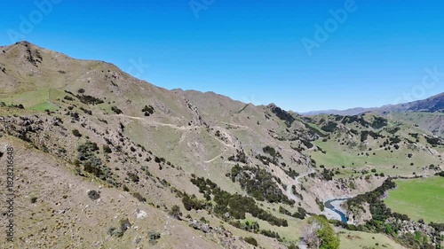 Aerial panorama showcasing a serene mountain valley with a winding river, lush green hills. 